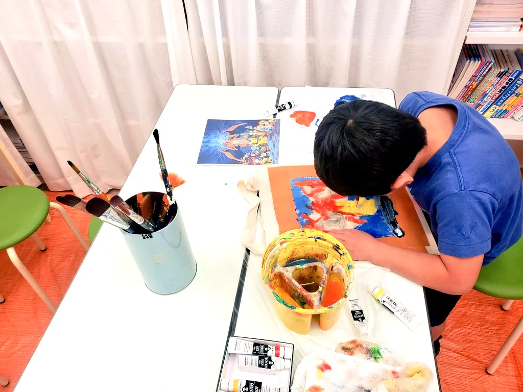 静物を見ながら絵の具で描く小学生