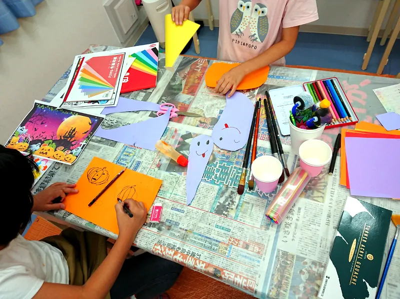 色紙と画材を使って制作する子供たちの手元