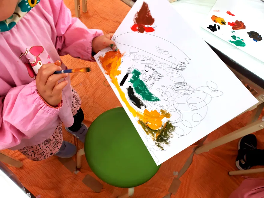 スモックを着て絵の具で描く子供