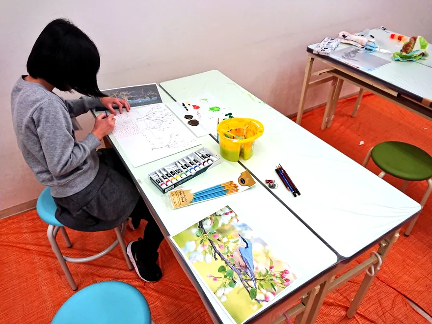 机に向かって絵を描く子供の後ろ姿